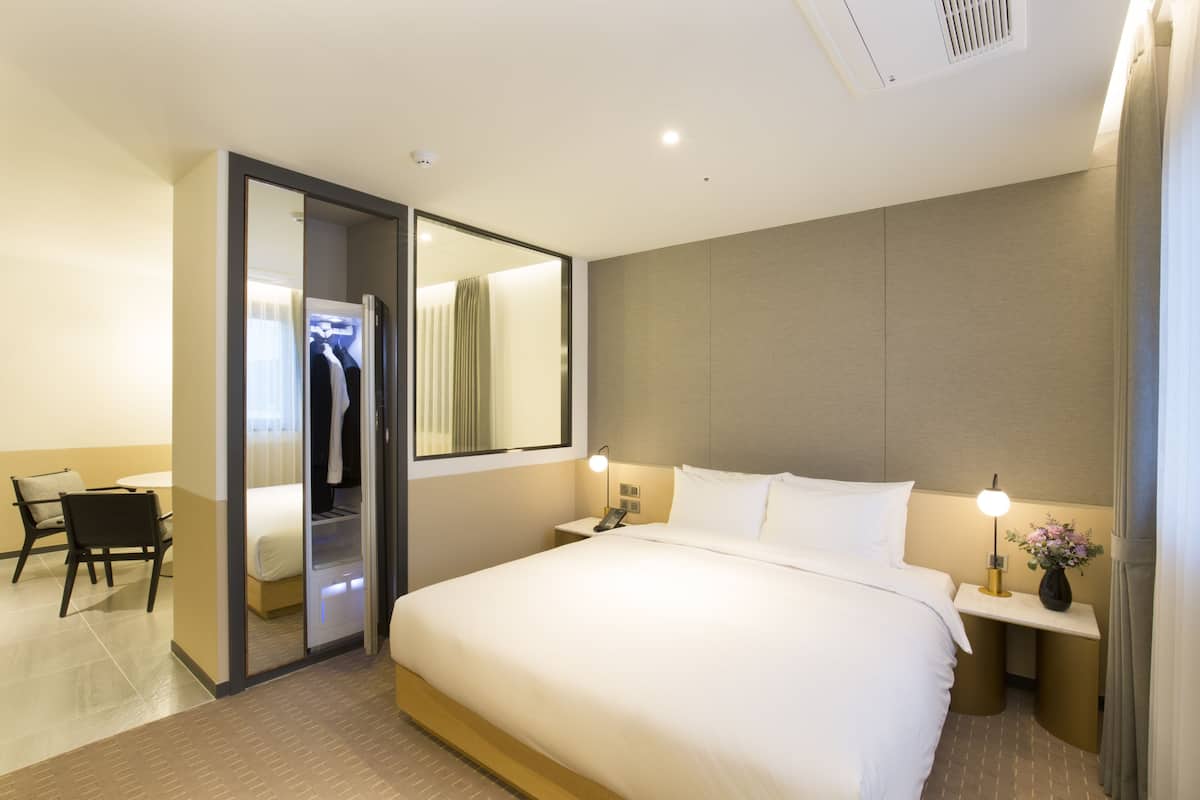 A hotel room with a large bed, bedside tables, a desk, and a wardrobe.