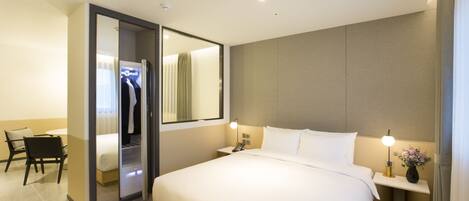 A hotel room with a large bed, bedside tables, a desk, and a wardrobe.