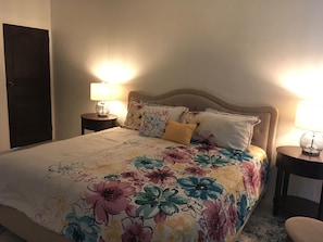 A neatly made bed with floral bedding, two bedside lamps, and a wooden headboard. - Villa Flagrantia, Paradise at your pleasure (Guana Bay)
