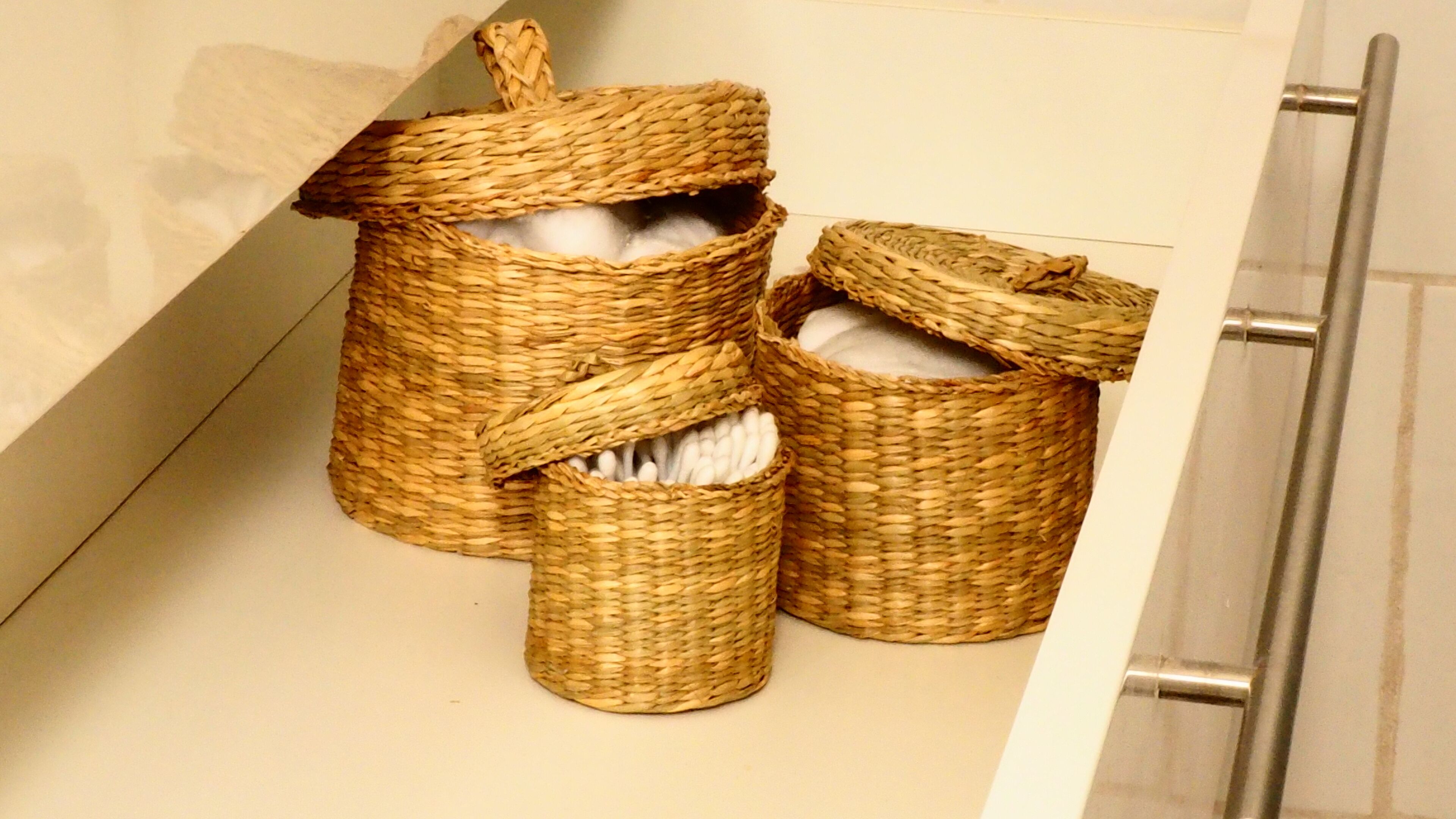 Three woven baskets on a bathroom counter.