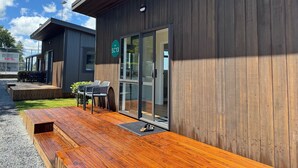 A modern building with a wooden exterior, a covered outdoor seating area with a table and chairs, and a sign indicating an eco-friendly location. - Cambridge TOP 10 Holiday Park (Cambridge)