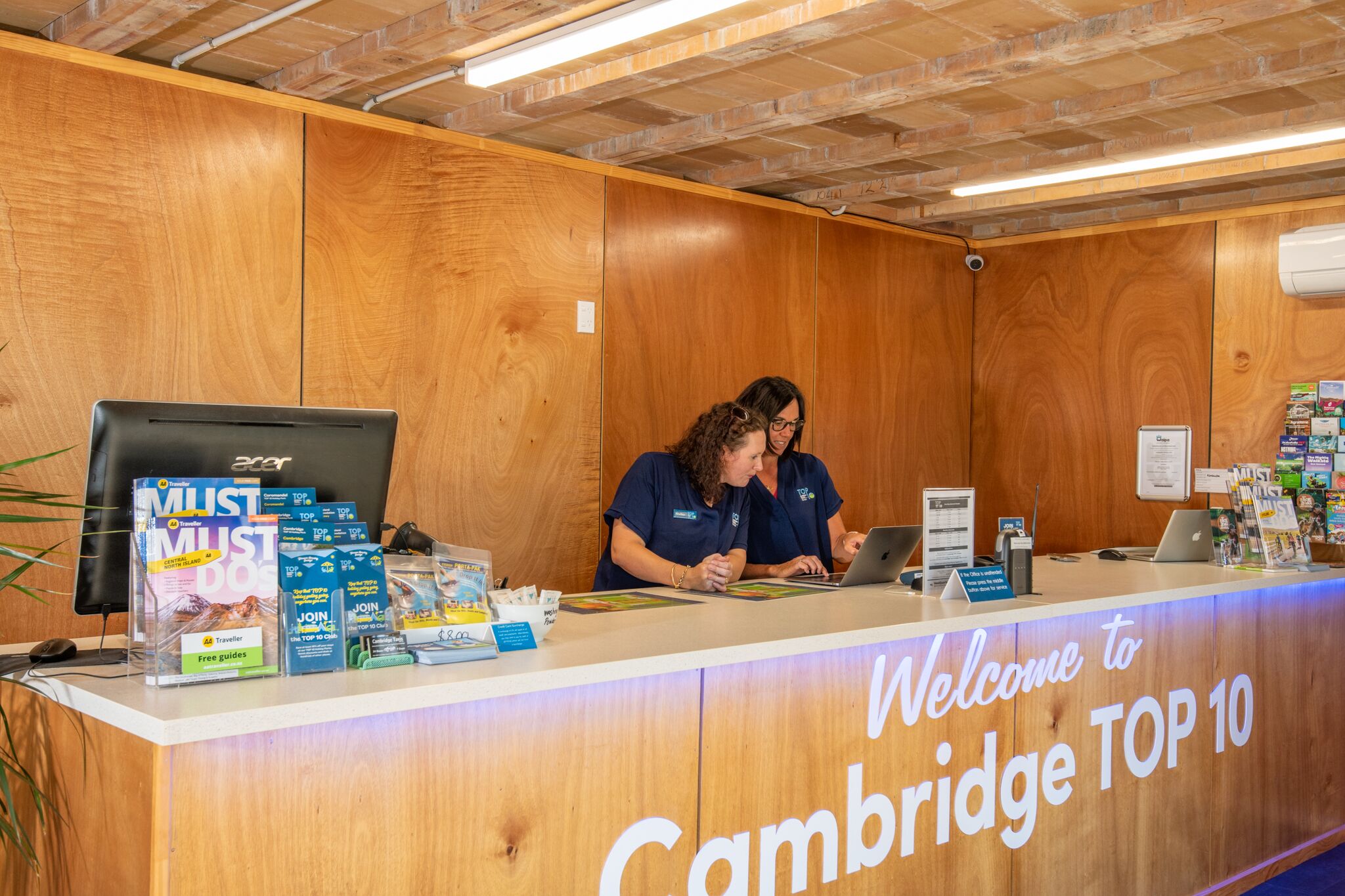 A reception desk with a wooden panel design, a laptop, and informational brochures.