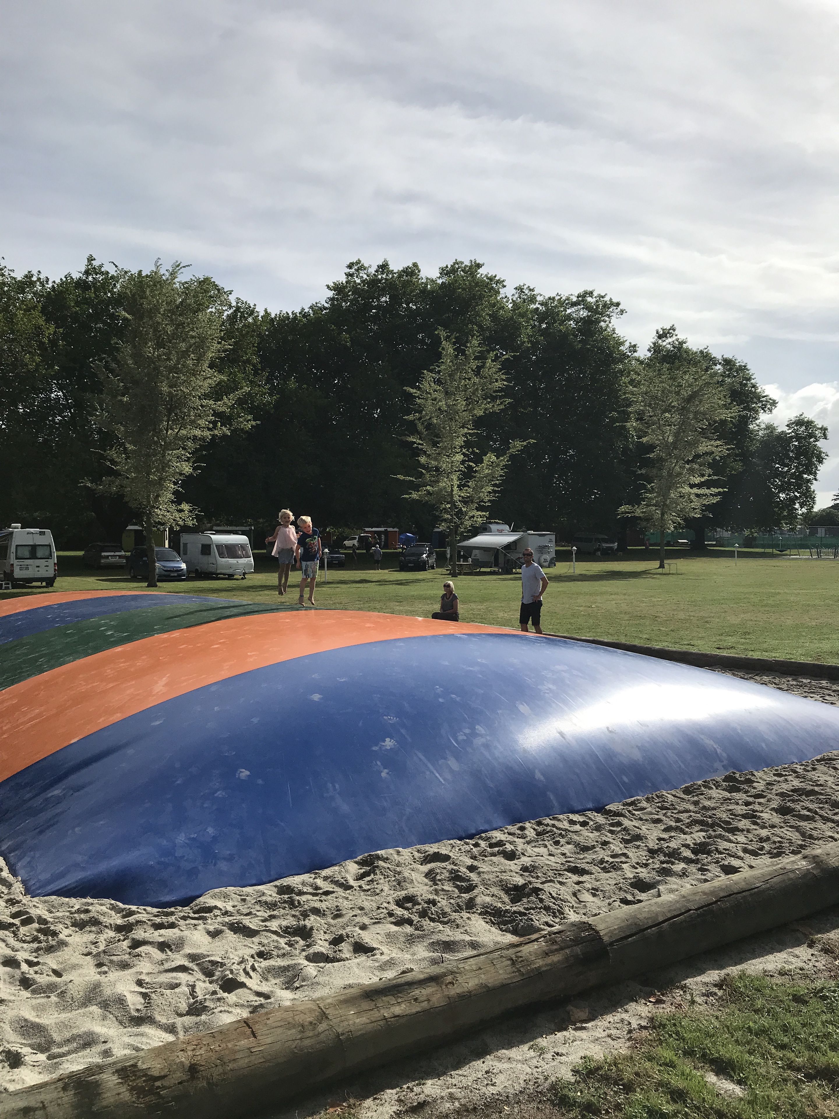 A sandy play area with a large blue and orange slide.