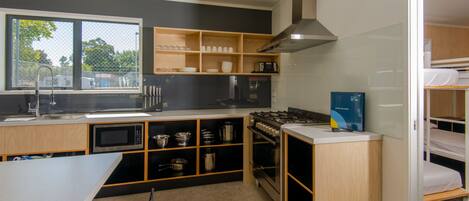 Una cocina compacta con estufa, microondas y estantes de madera.