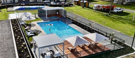 A swimming pool with lounge chairs and umbrellas, surrounded by a fenced deck area.
