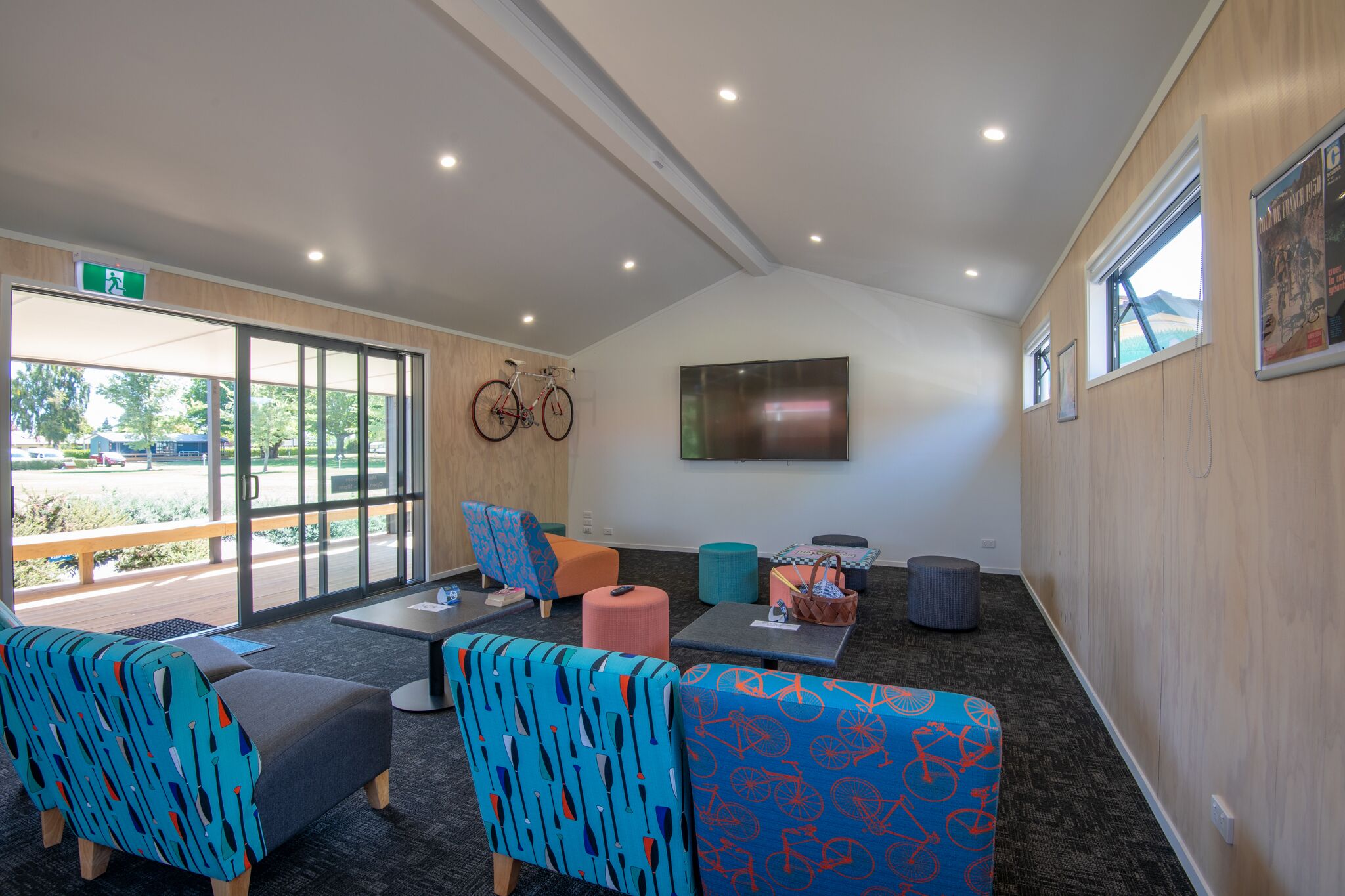 A modern lounge area with comfortable seating, a large TV screen, and a bike rack.