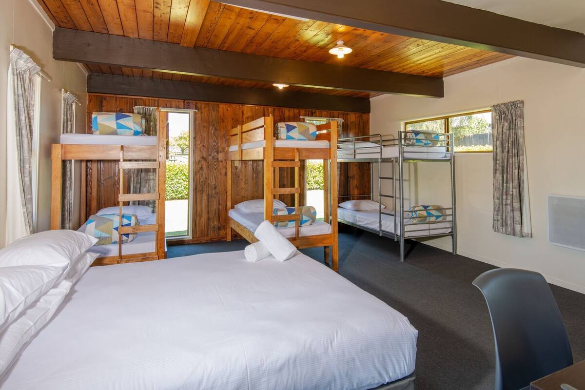 A room with bunk beds, a single bed, and a window.