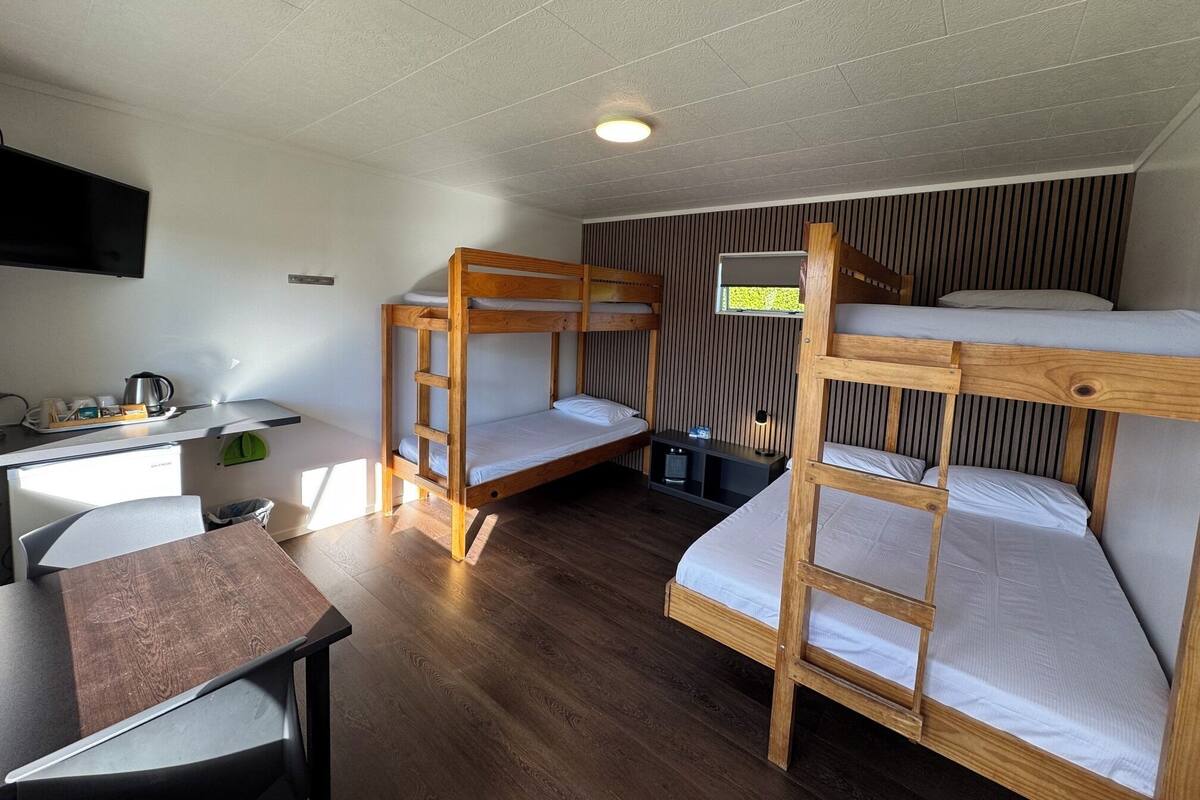 A bunk bed room with a desk and a TV.