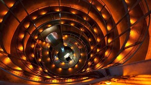 A spiral staircase with a central open area, surrounded by metal railings and illuminated by warm lighting. - Cambridge TOP 10 Holiday Park (Cambridge)