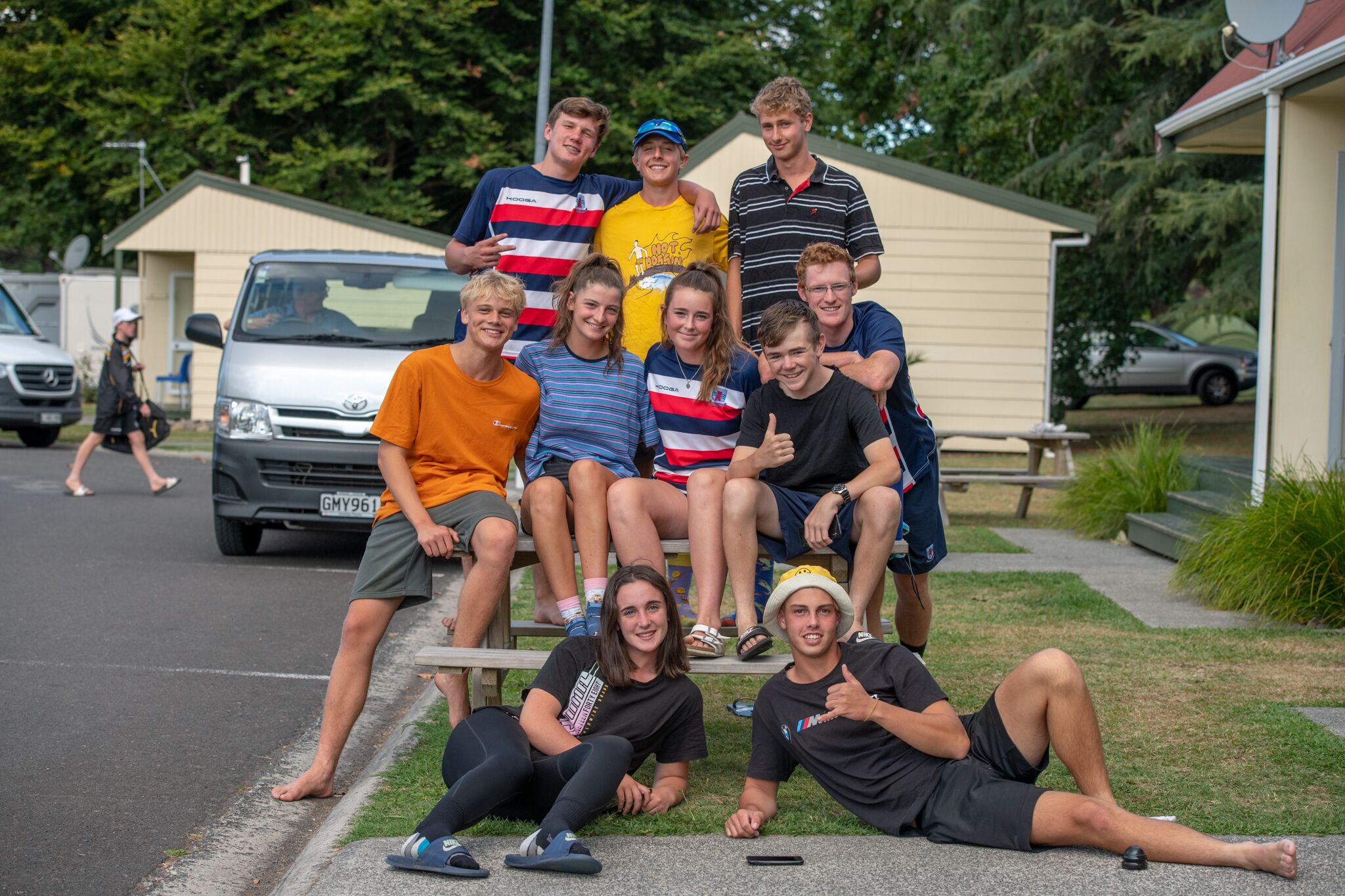 A group of people sitting and standing on a sidewalk in front of a house.