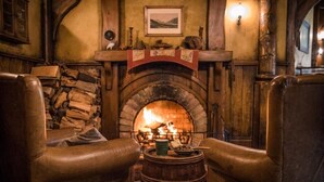 A cozy room with a stone fireplace, leather armchairs, and a wooden barrel. - Cambridge TOP 10 Holiday Park (Cambridge)