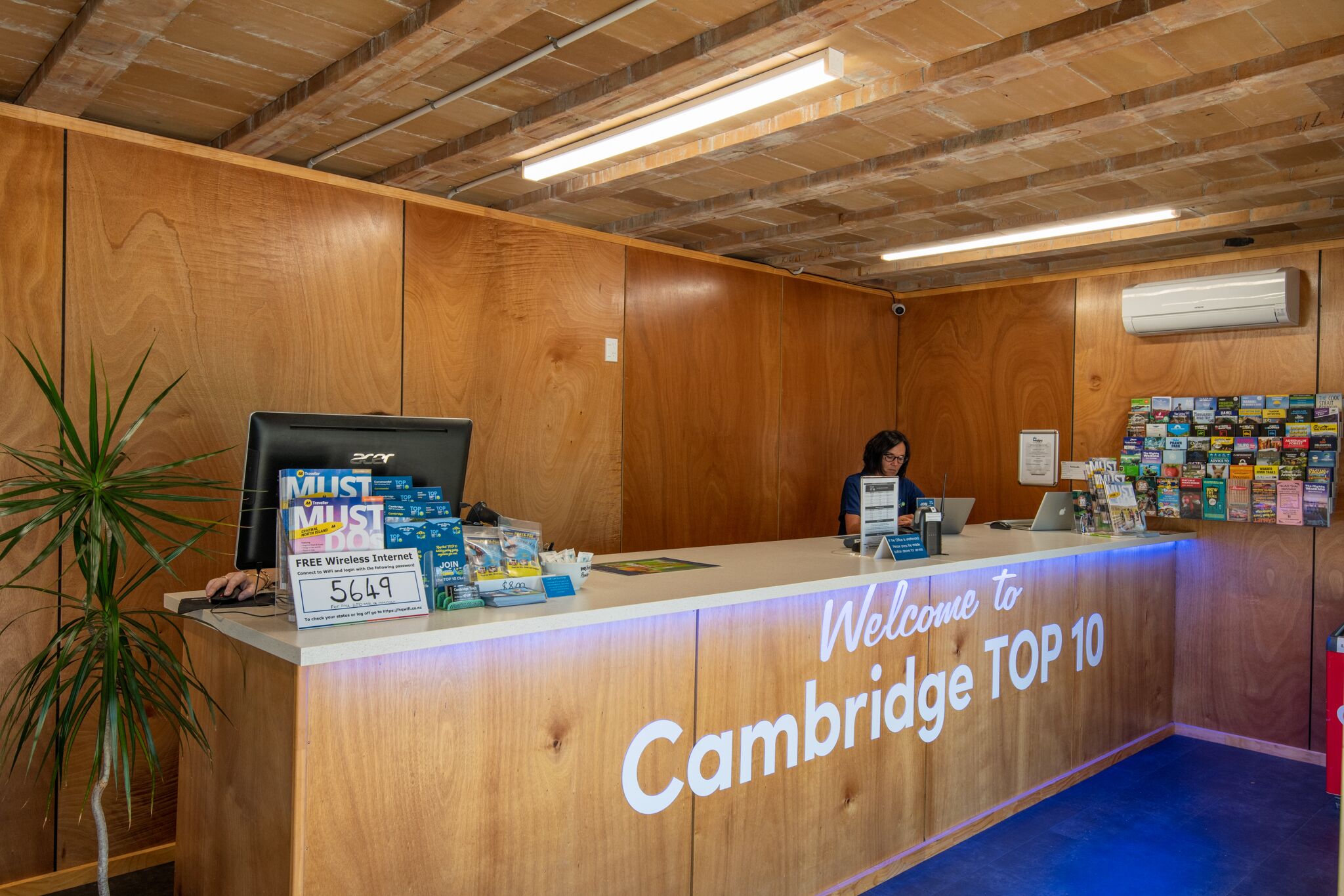 A reception desk at Cambridge TOP 10 with a wooden finish, a computer, and various informational materials.
