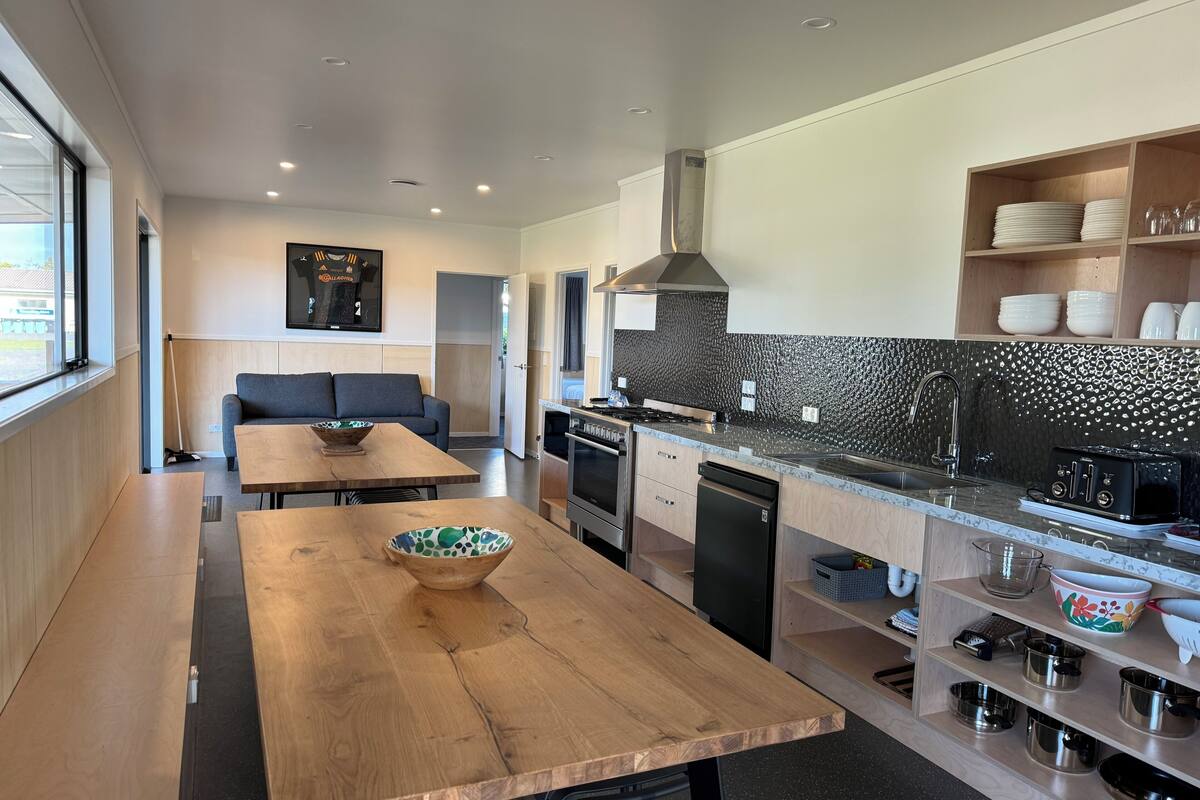 A modern kitchen with a wooden dining table, a built-in oven, and a black backsplash.