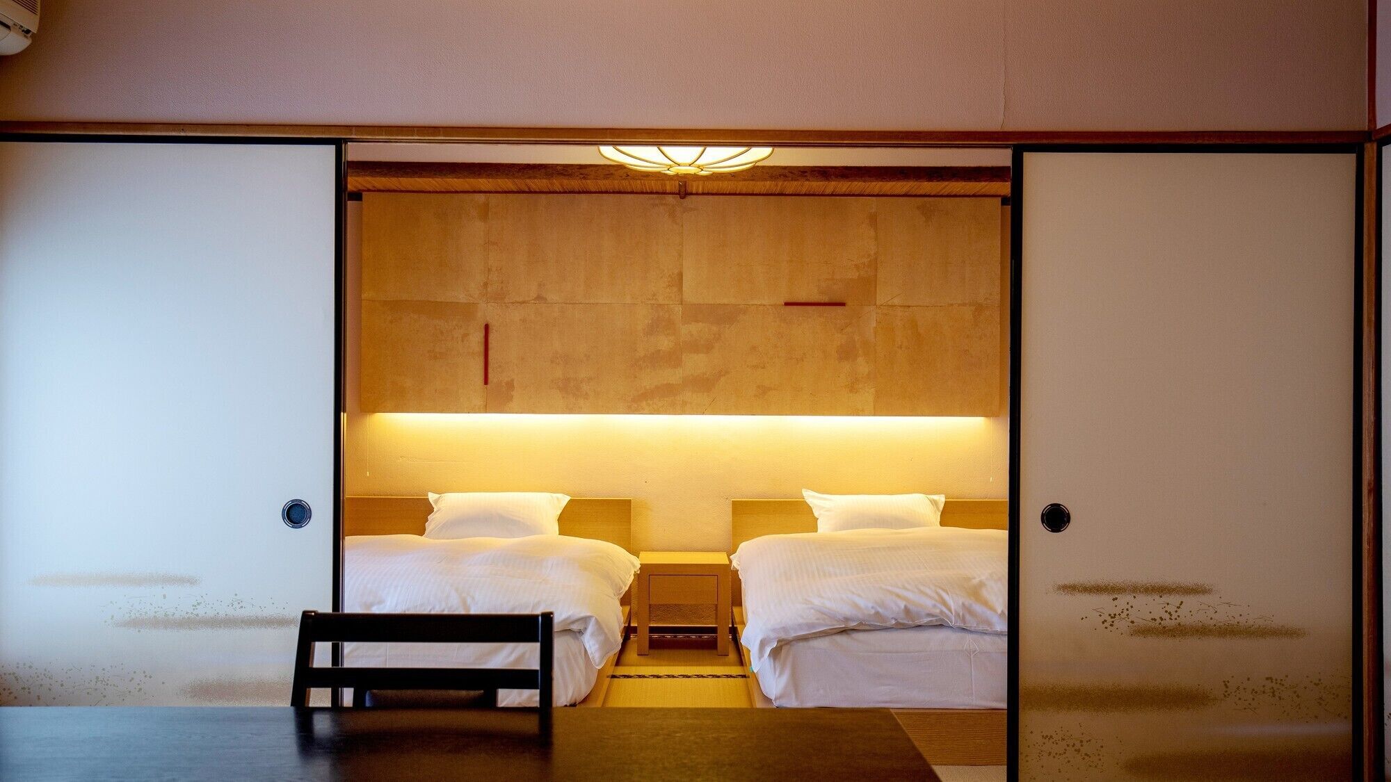 Una habitación de hotel con dos camas, un cabecero de madera y una mesita.