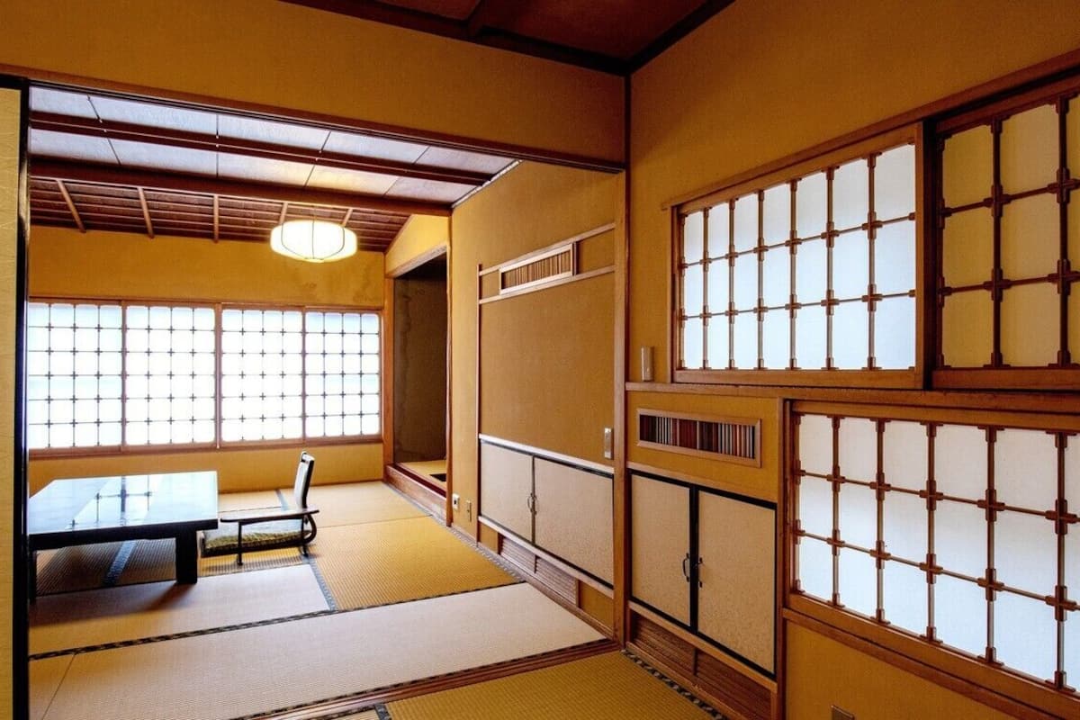 A traditional Japanese room with tatami flooring, sliding doors, and a low table with a bench.