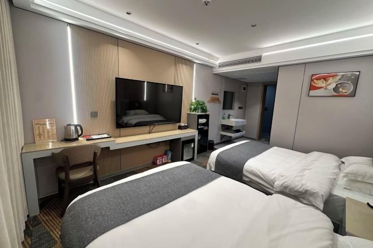 Una habitación de hotel con una cama, un escritorio, un televisor y una pequeña cocina.