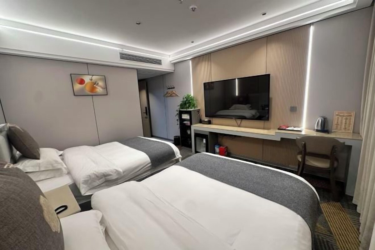 Habitación de hotel con dos camas, un escritorio, un televisor y un pequeño rincón de descanso.