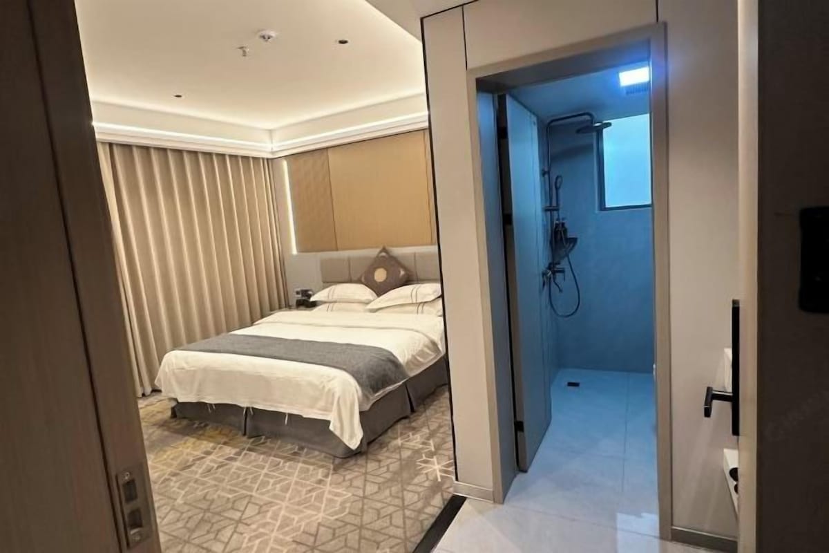 Una habitación de hotel con cama, ducha y puerta que da a otra habitación.