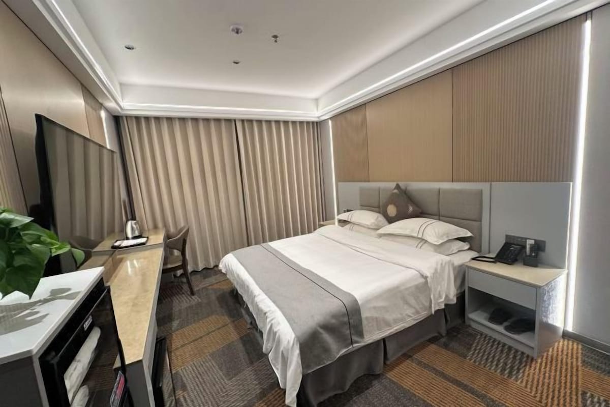Una habitación de hotel con cama, escritorio, silla y televisión.