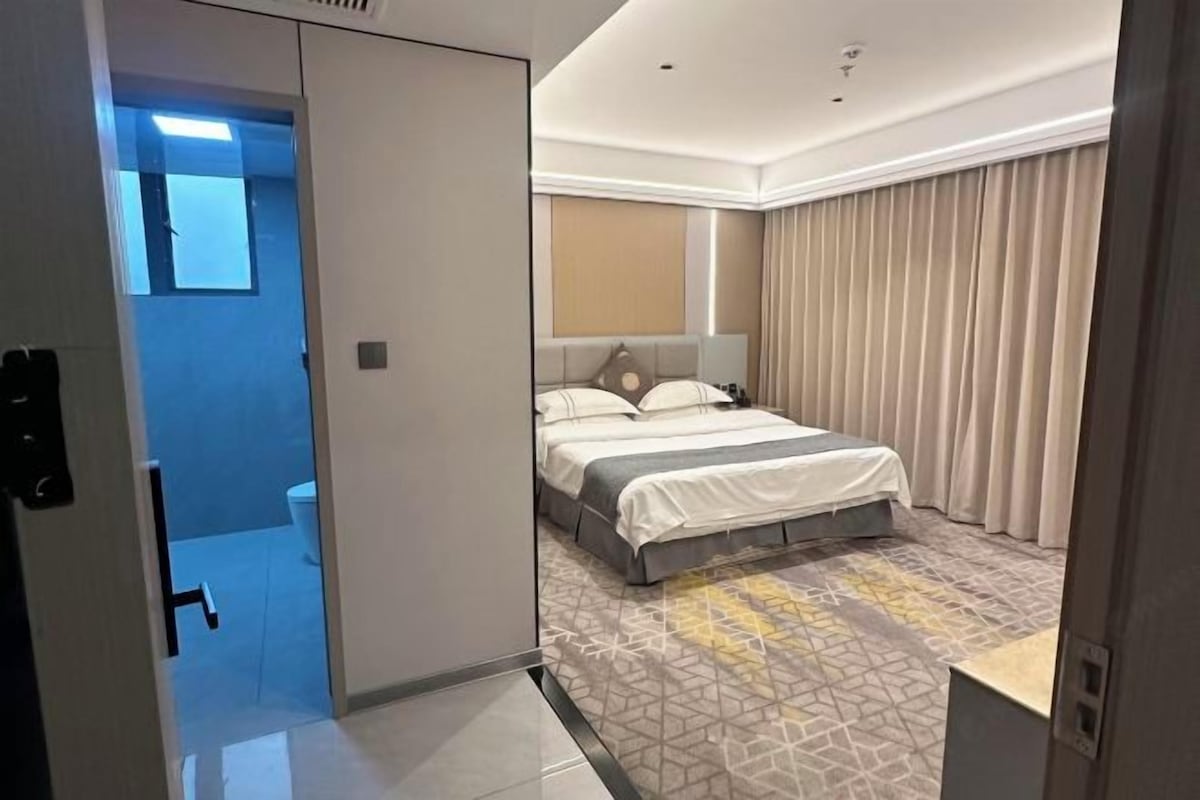 Una habitación de hotel con cama, baño y vistas al exterior.