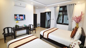 A hotel room with two beds, a desk, a chair, a TV, and a window with curtains. - Hoi An Bali Homestay (Da Nang)