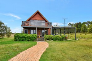 A two-story house with a balcony, a covered porch, and a brick pathway leading to the entrance.