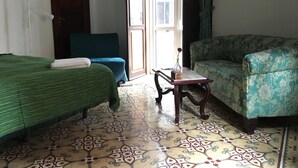 Ein Zimmer mit einem Bett, einem Sofa, einem Tisch und einem gemusterten Boden.