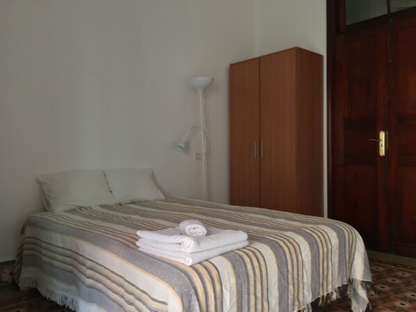 A bedroom with a bed, a wardrobe, and a bedside lamp.