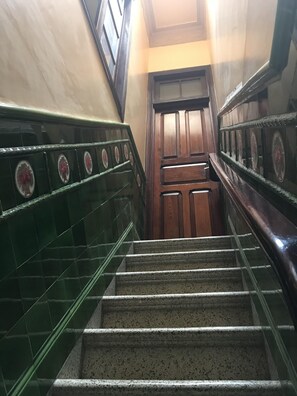 A staircase with green-tiled walls and a wooden door at the top.