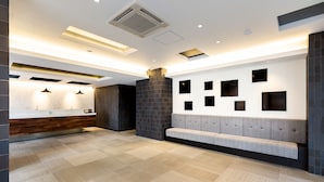 A modern hotel lobby with a reception desk, a seating area, and a tiled floor. - HOTEL M’s EST KYOTO STATION SOUTH (Kyoto)