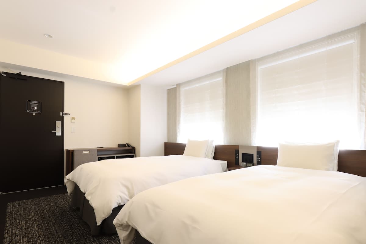 Une chambre d’hôtel avec deux lits, un bureau et une porte.