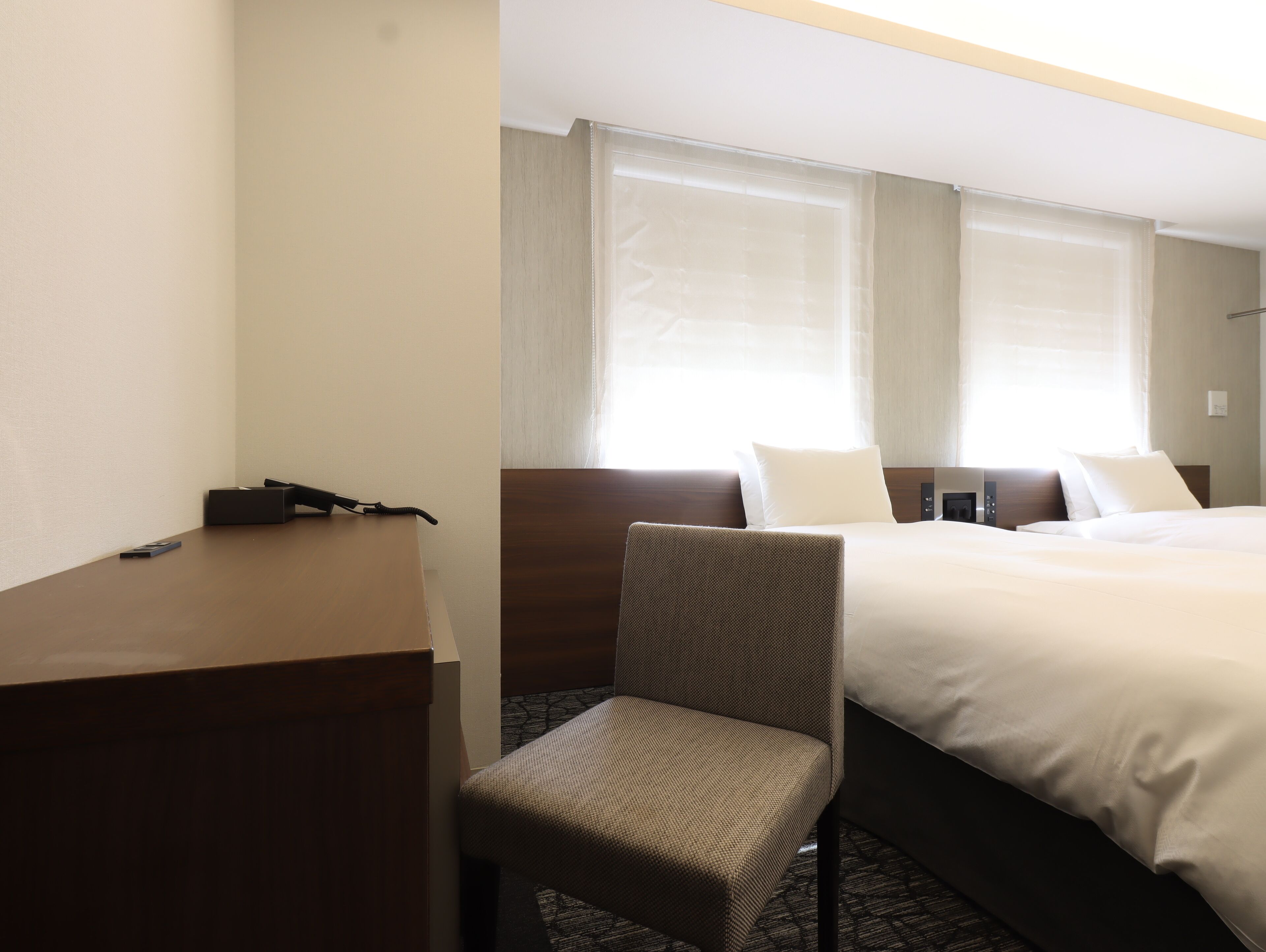 A hotel room with a bed, a chair, a desk, and a telephone.