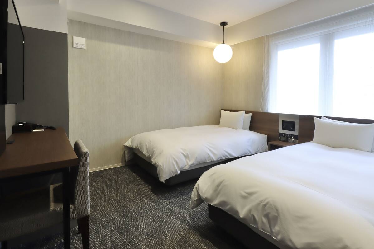 Une chambre d’hôtel avec deux lits, un bureau et une télévision.