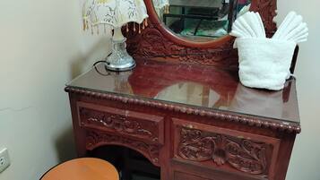 Un tocador de madera con espejo, una lámpara y una toalla.