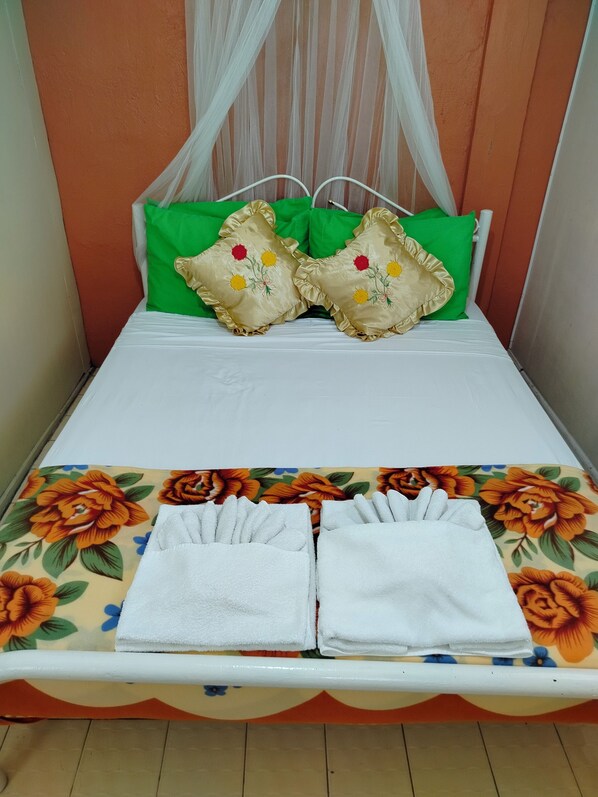 A bed with a floral bedspread, green pillows, and a white canopy. - Villa 301 B&B (Baclayon)