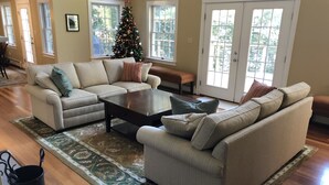 Een woonkamer met een beige hoekbank, een salontafel en een kerstboom.
