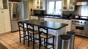 Een moderne keuken met een centraal eiland, roestvrijstalen apparatuur en een raam dat voor natuurlijk licht zorgt.