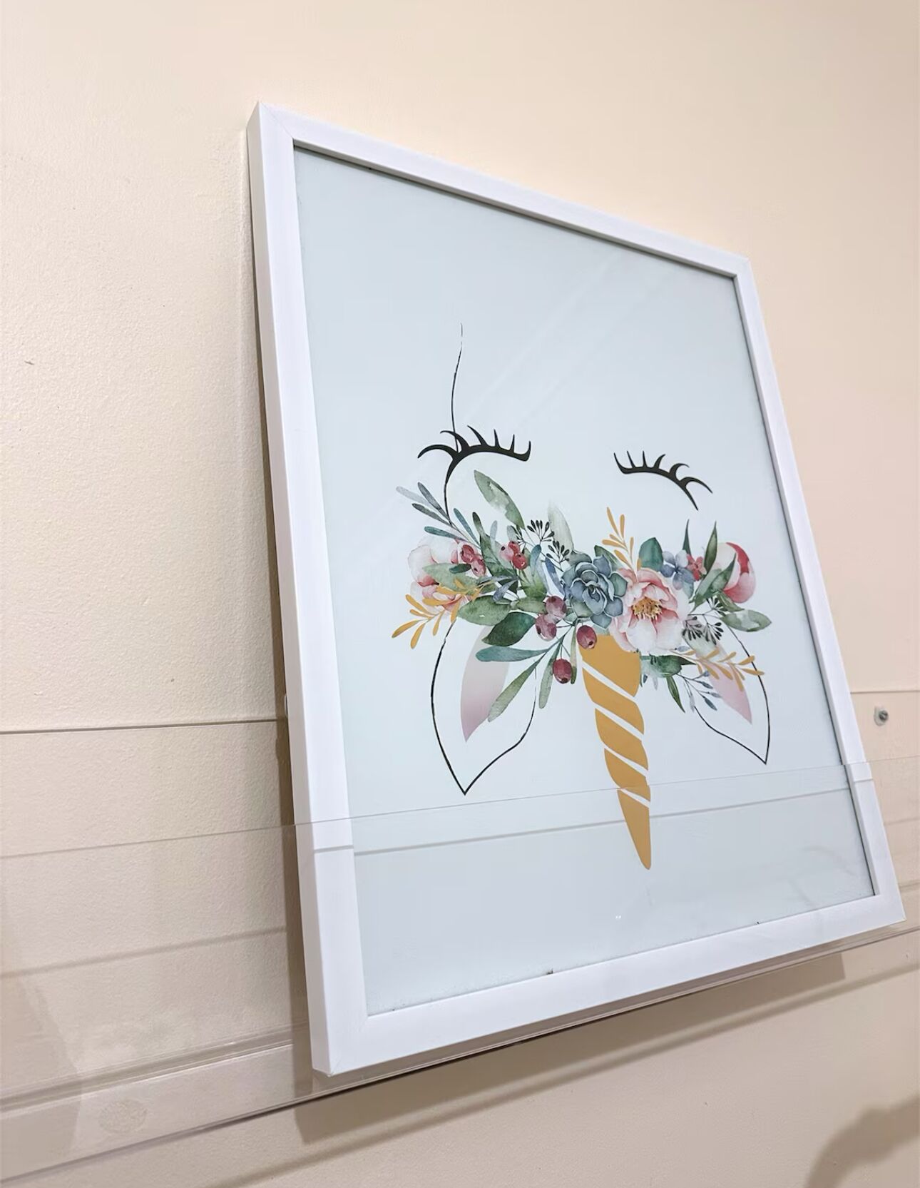 A framed artwork featuring a floral arrangement with a horn-like structure.
