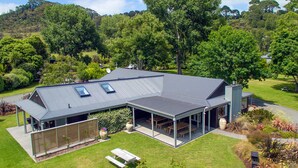 A modern house with a covered patio, a lawn, and a view of the surrounding hills.