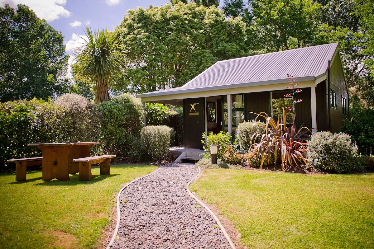 A building with a covered porch, a gravel path leading to it, and a picnic table.