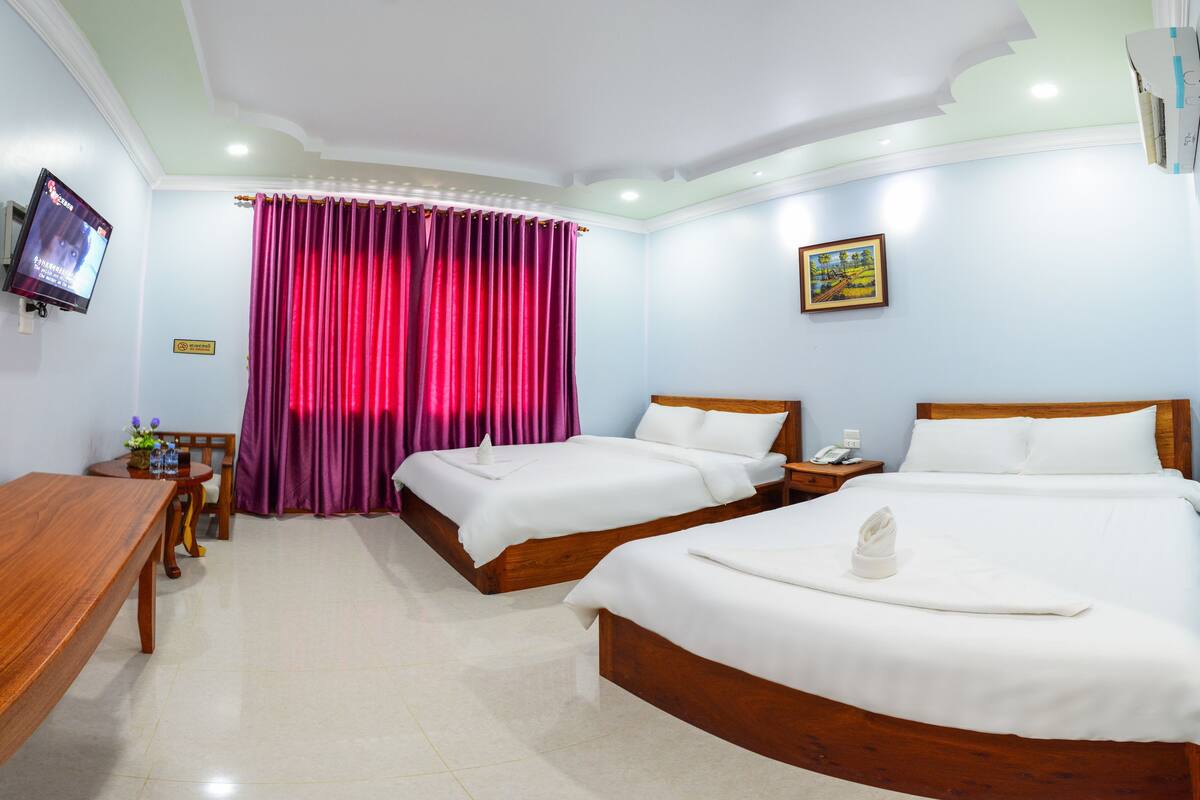 A hotel room with two beds, a TV, a painting, and a desk with a chair.