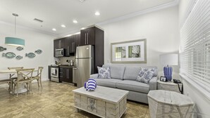 A modern kitchen with dark cabinets, a stainless steel refrigerator, and a microwave.