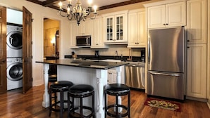 A kitchen with a central island, stainless steel appliances, and wooden flooring.