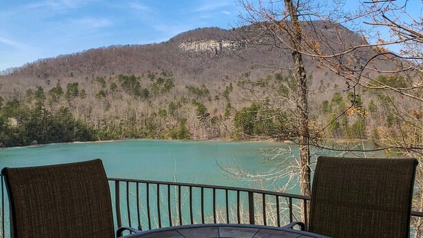 A table with two chairs facing a turquoise lake with a mountain in the background.