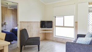 Una stanza con un letto, una televisione su un ripiano, una sedia, un divano e una finestra.