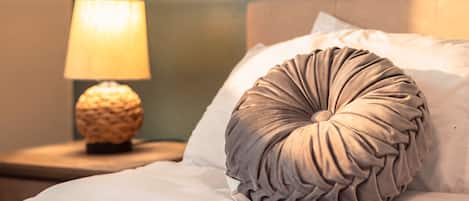 A bed with a textured pillow and a lamp on a bedside table.