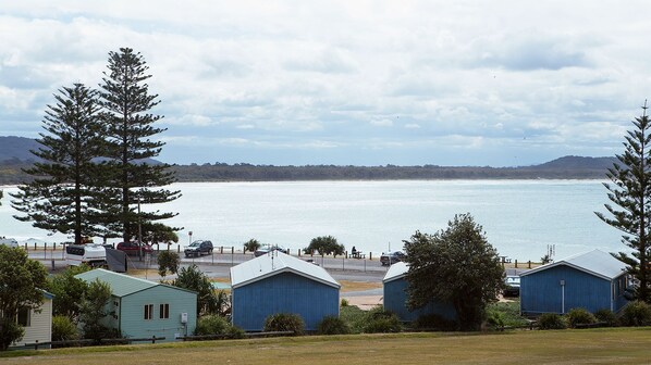 A coastal area with several small buildings, a clear view of the sea, and a distant mountain range. - Crescent Head Holiday Park (Crescent Head)