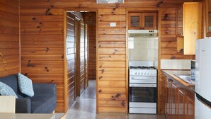 Eine kleine Küche mit Holzvertäfelung, einem Einbauofen und einem Kühlschrank.
