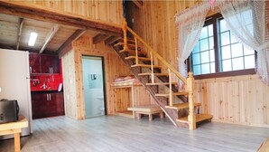 Un intérieur en bois comprenant un escalier, un coin cuisine et une porte donnant sur une autre pièce.
