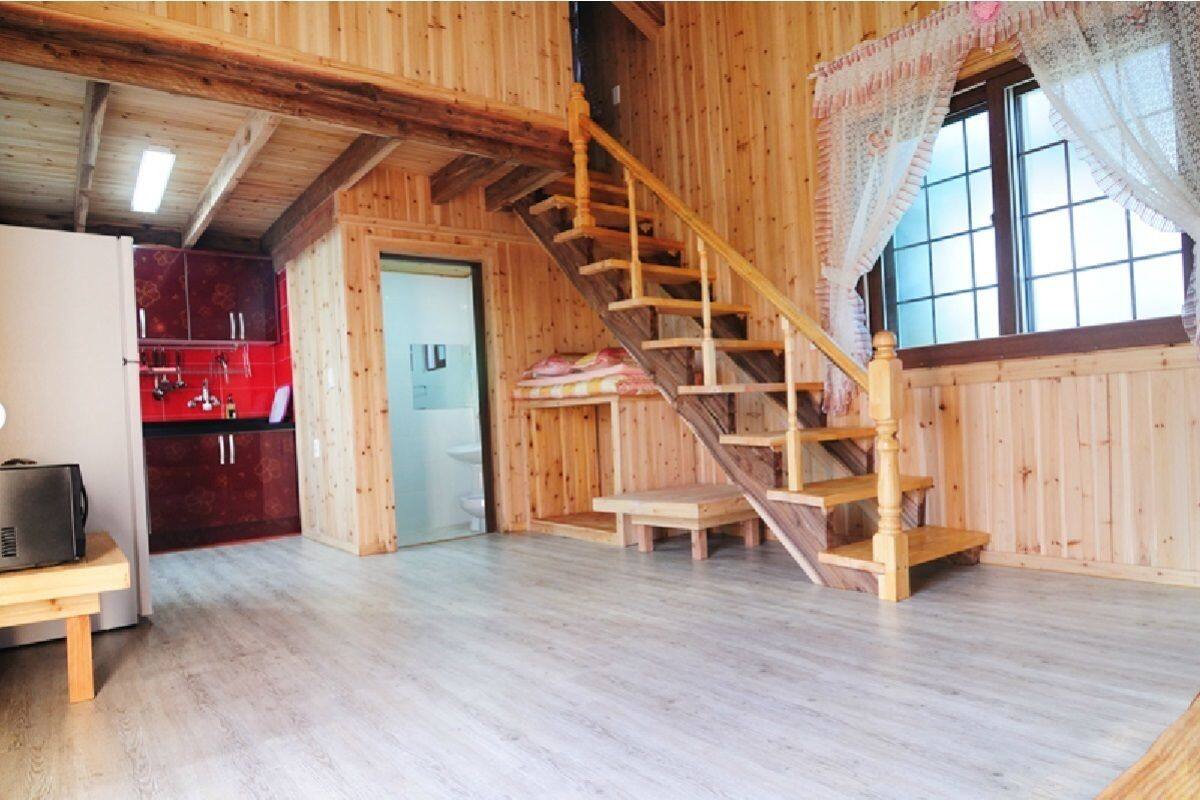 Un intérieur en bois comprenant un escalier, un coin cuisine et une porte donnant sur une autre pièce.